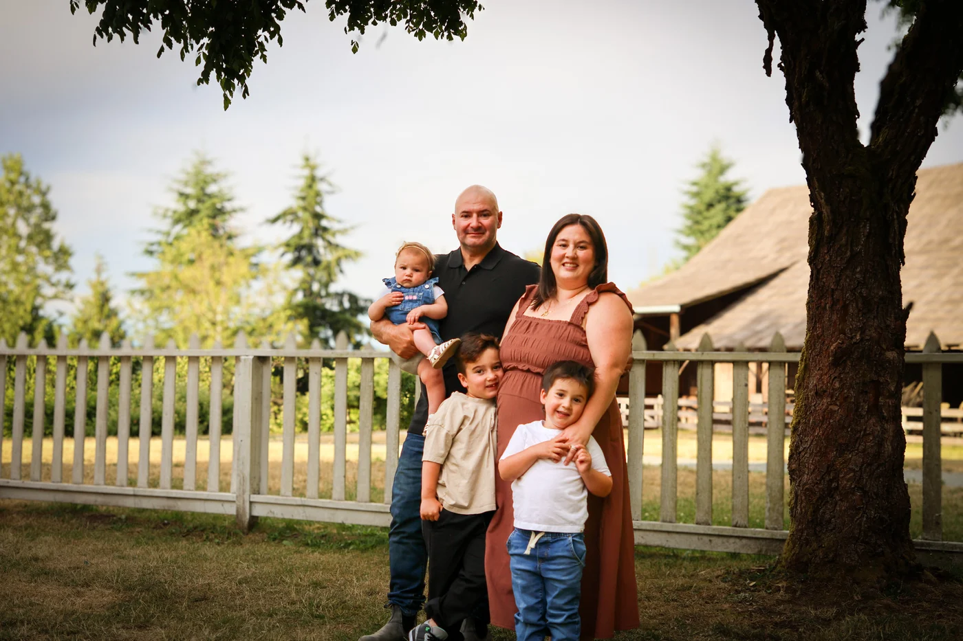 A family sharing a relaxed outdoor portrait beneath a tree